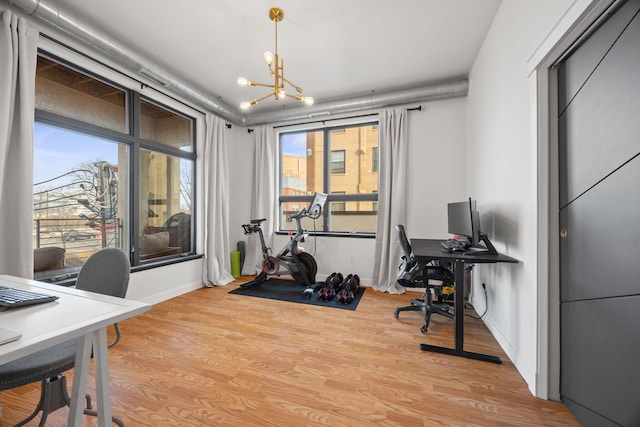 home office with baseboards, a notable chandelier, plenty of natural light, and light wood-style flooring