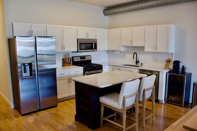 kitchen with appliances with stainless steel finishes, a sink, light countertops, white cabinetry, and decorative backsplash