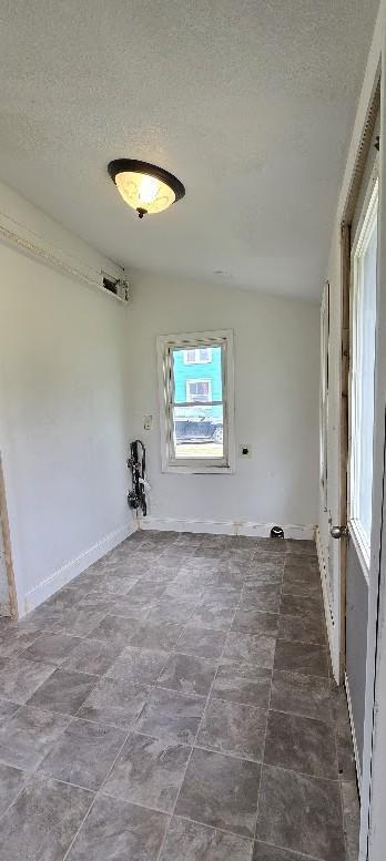 empty room featuring a textured ceiling and baseboards