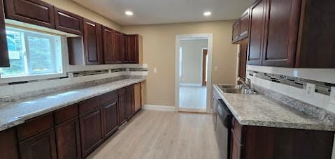 kitchen featuring dark brown cabinetry, baseboards, light wood finished floors, and a sink
