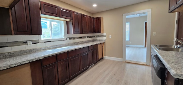 kitchen featuring light wood-style floors, backsplash, dishwasher, a sink, and baseboards