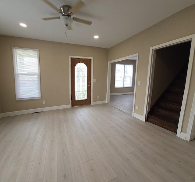 entrance foyer with baseboards, light wood-type flooring, ceiling fan, and stairs