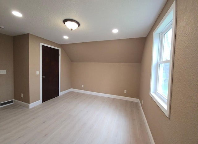 additional living space with visible vents, light wood-style flooring, and a healthy amount of sunlight