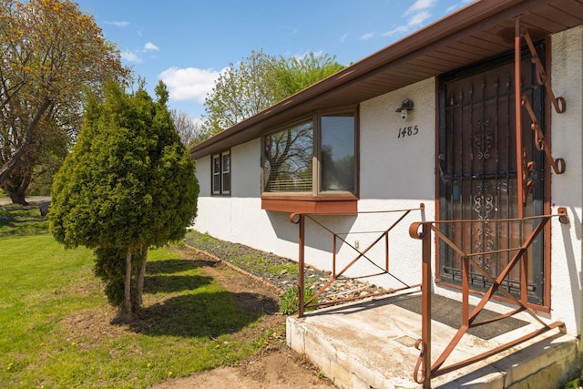 entrance to property featuring stucco siding and a yard