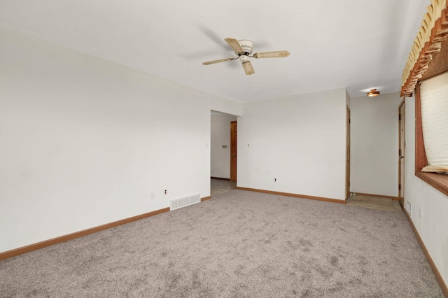 spare room with light carpet, ceiling fan, and baseboards