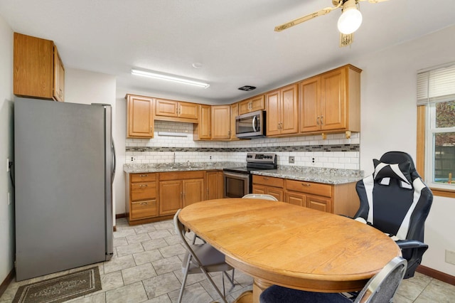 kitchen with appliances with stainless steel finishes, backsplash, ceiling fan, a sink, and baseboards