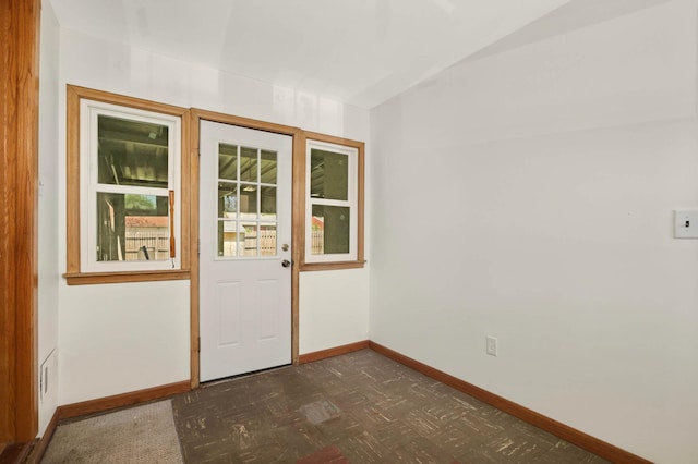 doorway to outside with baseboards and dark flooring