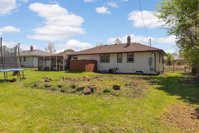 rear view of property featuring a trampoline and a chimney