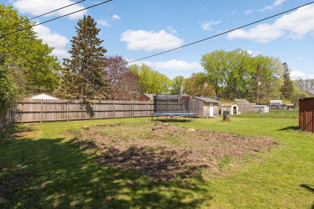 view of yard with a trampoline, a storage unit, and an outbuilding