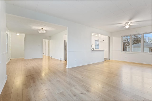 6715 Bloomington Ave, Richfield, MN 55423 - unfurnished living room featuring baseboards, a ceiling fan, light wood finished floors, and a sink