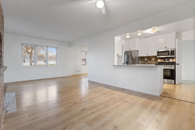 6715 Bloomington Ave, Richfield, MN 55423 - kitchen featuring open floor plan, white cabinetry, a ceiling fan, light wood-style flooring, and appliances with stainless steel finishes