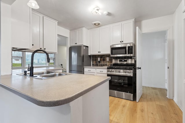 6715 Bloomington Ave, Richfield, MN 55423 - kitchen featuring decorative backsplash, appliances with stainless steel finishes, a sink, a peninsula, and white cabinetry