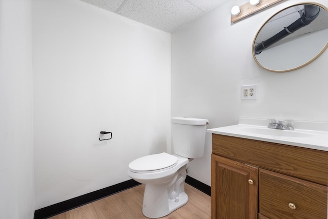 6715 Bloomington Ave, Richfield, MN 55423 - half bath featuring wood finished floors, vanity, baseboards, toilet, and a drop ceiling