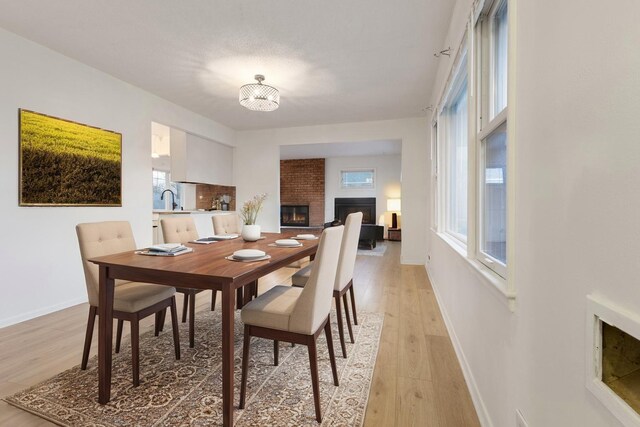 6715 Bloomington Ave, Richfield, MN 55423 - dining area with baseboards, a brick fireplace, and light wood-type flooring