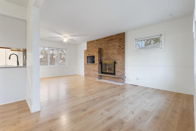 6715 Bloomington Ave, Richfield, MN 55423 - unfurnished living room with light wood-type flooring, a brick fireplace, and a ceiling fan