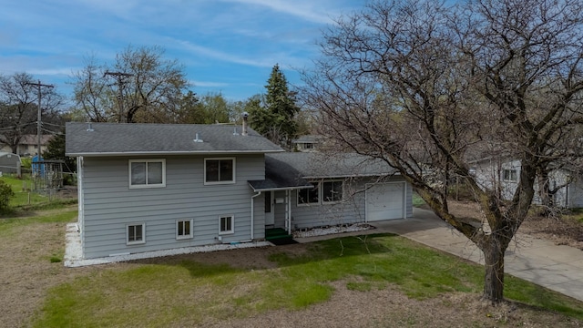 tri-level home featuring roof with shingles, an attached garage, driveway, and a front lawn