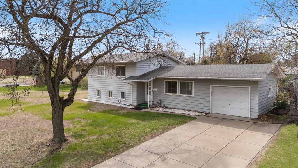 6223 Brooklyn Dr, Brooklyn Center, MN 55430 - tri-level home with concrete driveway, a shingled roof, a front yard, and a garage