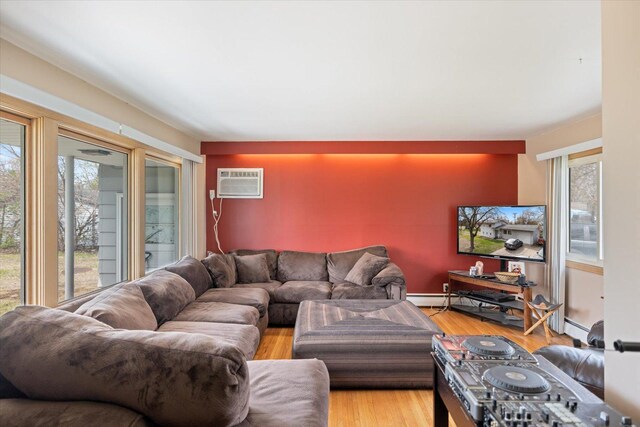 living room with a baseboard heating unit, light wood finished floors, and a wall mounted AC