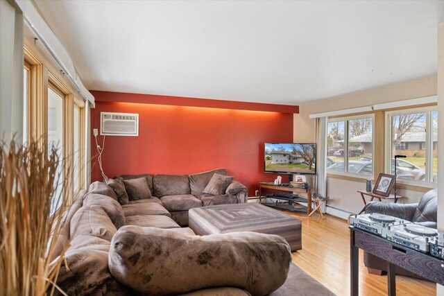living area with light wood-style floors and a wall unit AC