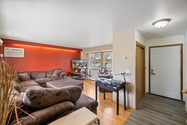 living room featuring a wall mounted air conditioner and light wood-style flooring