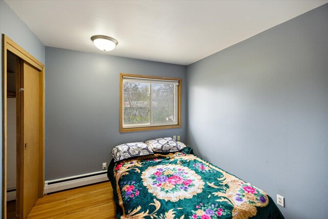 bedroom with a baseboard radiator and wood finished floors