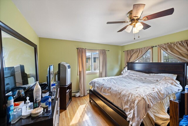 bedroom with a ceiling fan, multiple windows, and light wood-style flooring