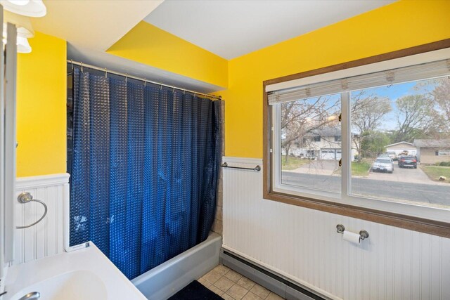 bathroom with tile patterned floors, shower / bath combo, wainscoting, and a baseboard heating unit
