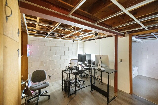 unfinished basement with concrete block wall and wood finished floors