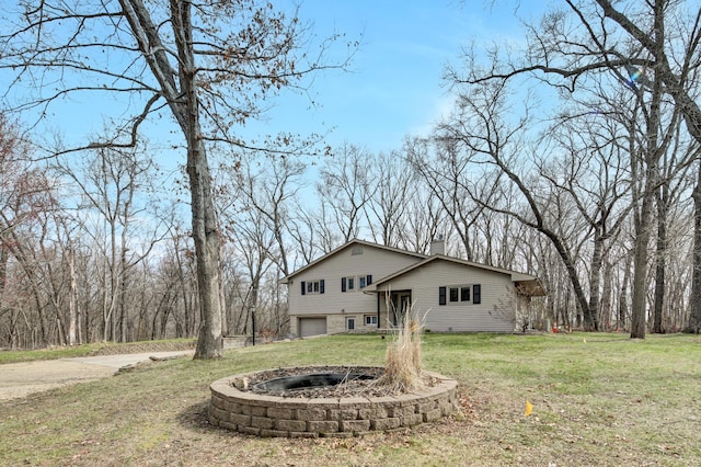 back of house with a lawn, a garage, and a chimney