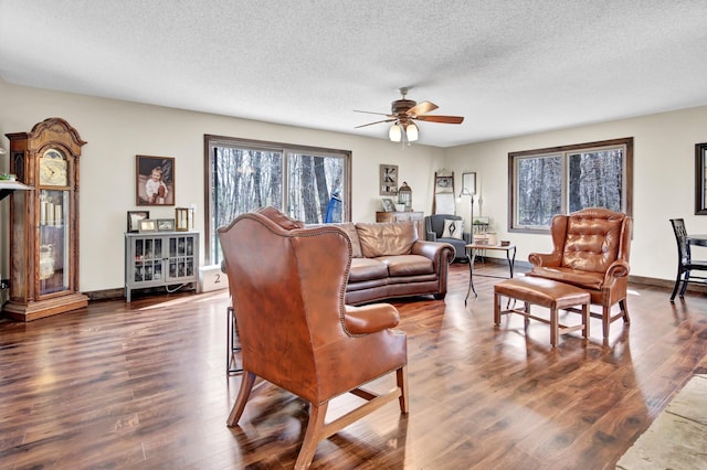 living room with baseboards, a ceiling fan, dark wood-style floors, and a textured ceiling