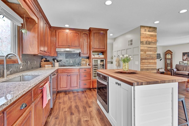 kitchen with beverage cooler, butcher block countertops, recessed lighting, a sink, and stainless steel appliances