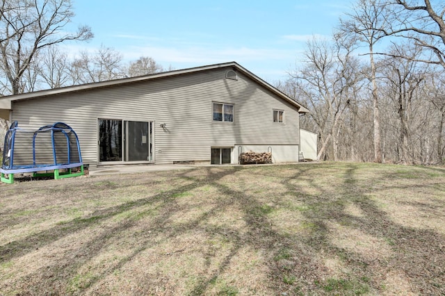 rear view of house with a trampoline and a yard