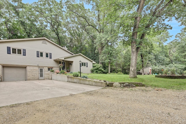 73466 318th Ave, Lake City, MN 55041 - tri-level home featuring concrete driveway, stone siding, a front lawn, a garage, and view of wooded area