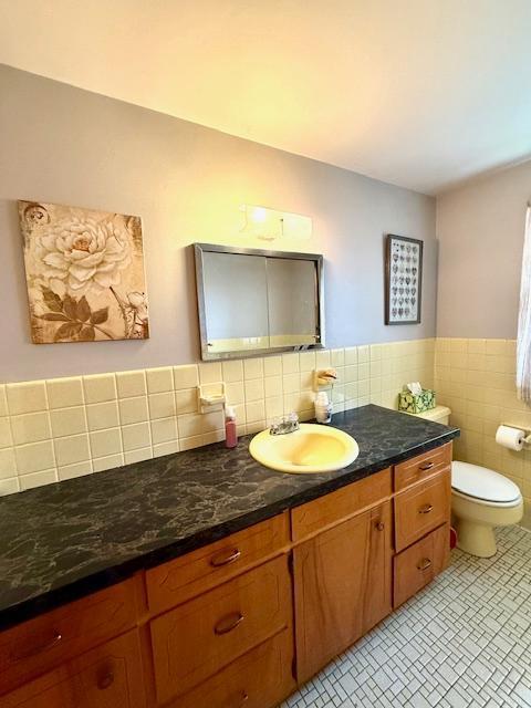 15497 Meiners Rd, Mayville Twp, MN 55921 - bathroom with vanity, toilet, tile patterned floors, and tile walls