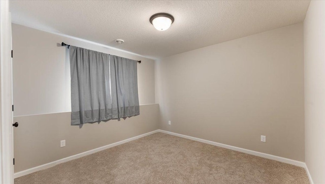 carpeted empty room with baseboards and a textured ceiling