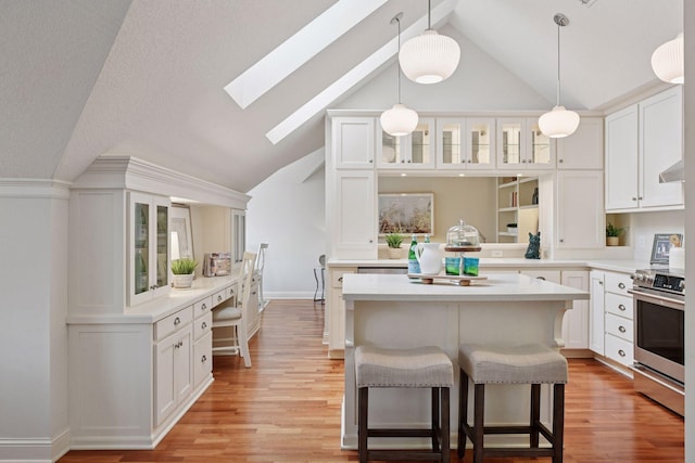 205 Mill St Unit S301, Excelsior, MN 55331 - kitchen with stainless steel range, a skylight, a kitchen bar, glass insert cabinets, and white cabinetry