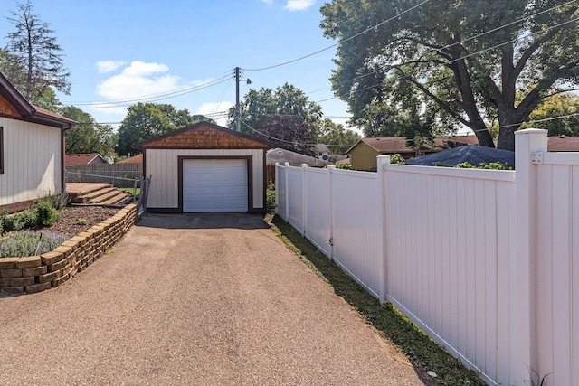 detached garage featuring driveway and fence