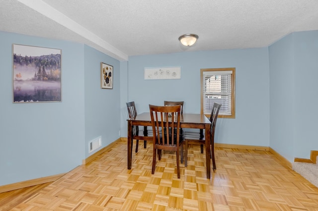 dining space featuring baseboards, visible vents, and a textured ceiling