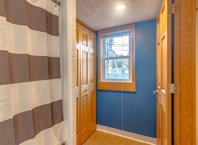 full bath with a textured ceiling, curtained shower, and tile patterned flooring