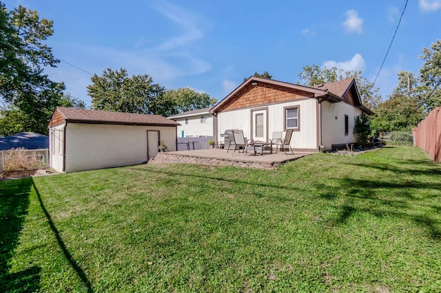 back of house featuring a fenced backyard, an outbuilding, a yard, and a patio area