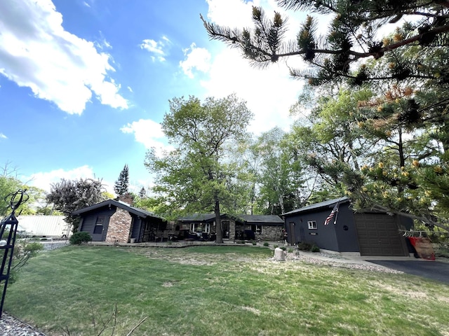 view of front of house with a garage, a front yard, a chimney, and asphalt driveway