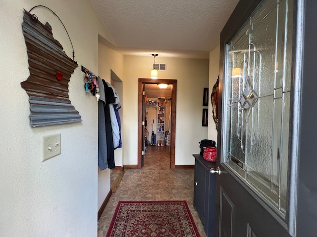 hallway featuring baseboards and a textured ceiling
