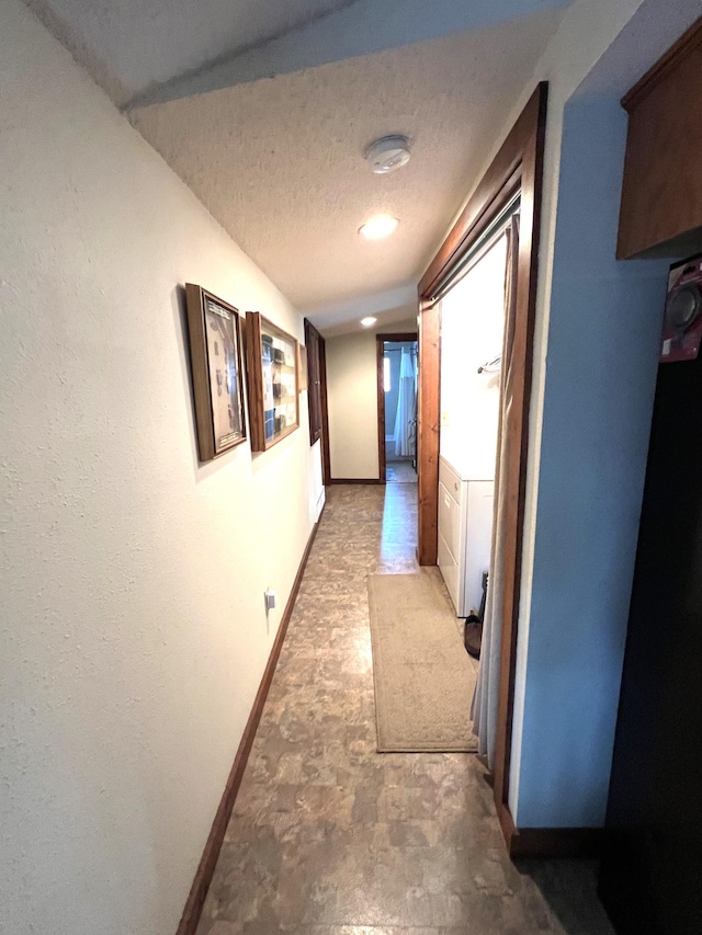 hallway with baseboards and a textured ceiling