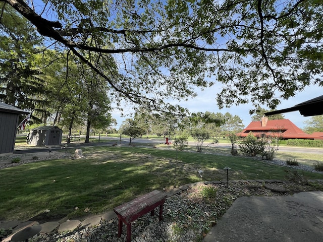 view of green lawn with a storage unit and an outbuilding