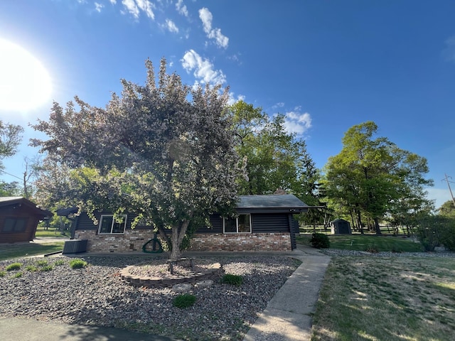view of front of home with brick siding, central AC, and a front yard