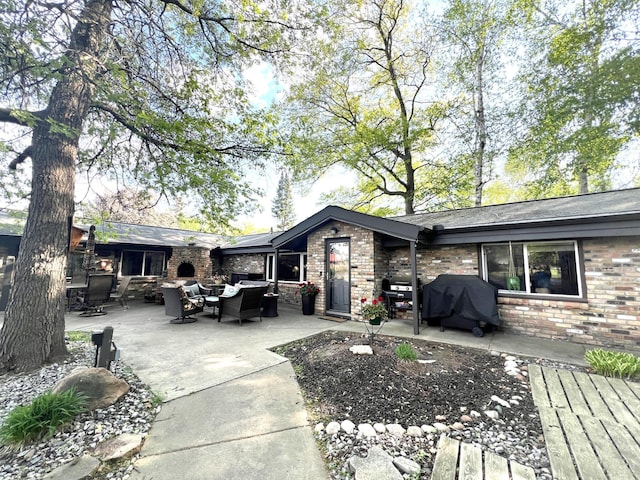 back of property featuring an outdoor living space, brick siding, and a patio area