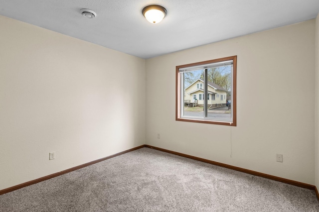 carpeted empty room featuring baseboards