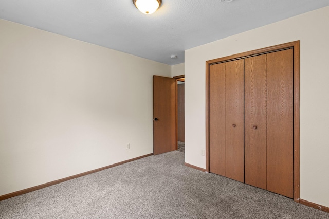 unfurnished bedroom featuring baseboards, carpet floors, and a closet