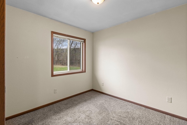 carpeted empty room featuring baseboards