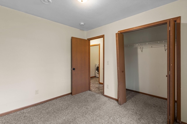 unfurnished bedroom featuring baseboards, washer / dryer, a closet, and carpet flooring
